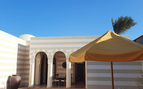 view of a swimming pool with orange and white umbrella and clear blue skies